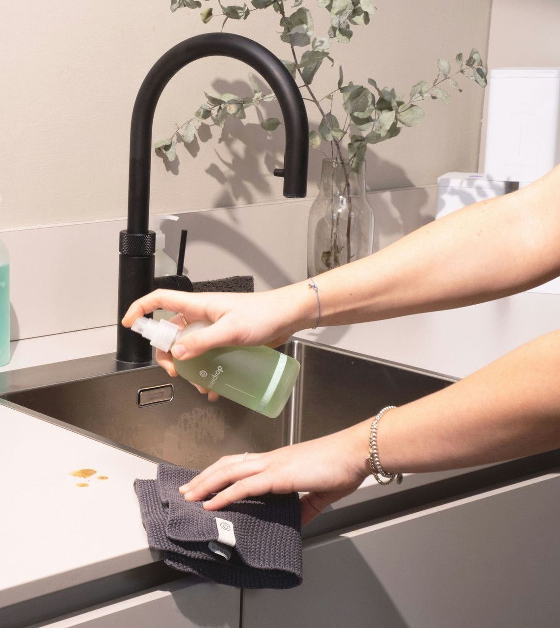 a woman is cleaning a kitchen sink with a rag